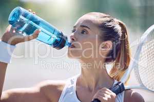 Health, fitness and water, a woman tennis player on a break, drinking from a plastic bottle during a match on the court. Beautiful young lady playing sports, training for a healthy summer lifestyle.