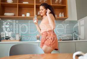 Playful, cheerful and joyful woman dancing and enjoying leisure morning in the kitchen while drinking milk. Excited latin woman having fun, celebrating and happy in the morning at home