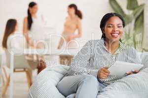 Creative black woman on social media, with tablet and checking online while on a work break. Happy young lady boss of ecommerce startup, relaxing before a business meeting business with her girl team