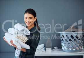 Clean linen can always make me smile. Cropped portrait of an attractive young woman carrying a pile of towels while doing laundry at home.