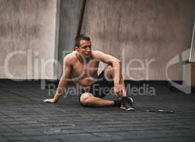 Taking a break from an insane workout. a young man taking a break while working out in a gym.