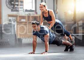 Fitness, strong and wellness couple exercising, training or workout exercise inside gym. Sporty professional woman and man or trainer doing pushup and balance in a physical endurance session