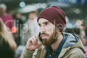 My bus should be here soon... a handsome young man making a phonecall while sitting in a bus station.