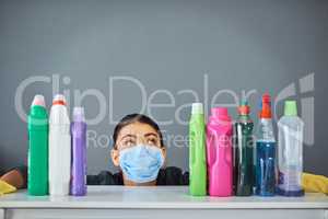 No germ will go undetected. Studio shot of an attractive young woman wearing a mask while surrounded by cleaning products.