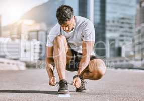 Wellness and fitness runner ties shoes lace before running in a city street during summer. Healthy man athlete prepare sneaker for a comfortable fit for a sport exercise, training or marathon workout