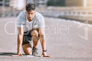 Runner in starting position for race, run or cardio for healthy exercise, workout or fitness in urban city. Active, fit and serious male sports athlete ready for training, running fast and sprint