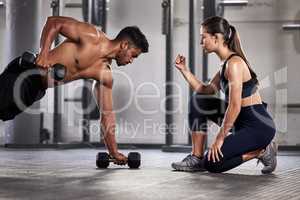 Training, exercise and motivation with a fitness coach or personal trainer and her bodybuilder student during a workout in the gym. Health, sports and wellness with a heathy athlete exercising