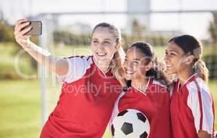 Selfie, soccer and sports team smiling and feeling happy while posing for a social media picture. Diverse and young girls standing together on a football field. Friends and teammates enjoying a match