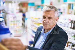 Found you. a well dressed mature man browsing a pharmacys shelves looking for the right medication to buy.