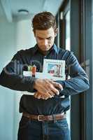 Depressed about his dismissal. an unhappy businessman holding his box of belongings after getting fired from his job.