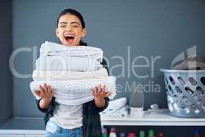 I love clean linen. an attractive young woman carrying a pile of towels while doing laundry at home.