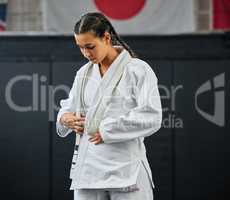 Mma, karate and self defense with a young woman getting ready in her gi or uniform for training, exercise and practice. Workout, sport and fighting with a female athlete standing in a gym or studio