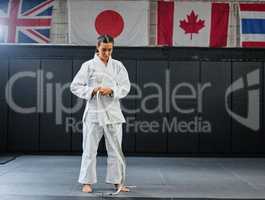 Professional karate student dressing and prepare for practice in a dojo or club. Female mix martial art athlete tying belt in training for a fight, competition or exercise workout in a sport studio