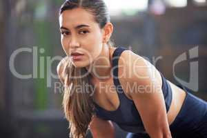 Fitness, gym and athletic woman taking a break and resting after a workout. Portrait of a fit and healthy woman looking tired after exercising and being active at a health and wellness facility