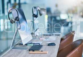 Headphone or headset in an empty call center office with computer monitor display for online customer service or support. Helpdesk hotline assistance gadgets and crm equipment in workplace or station