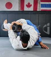. Male martial arts, fighting at a dojo and holding his opponent. Karate, sports and taekwondo adults training at the gym for a fight. Athlete, aikido and practicing for an international competition.