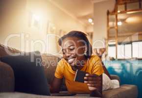 Online shopping young, happy and smiling African lady with bank, credit or gift card. Excited, comfortable and cheerful ethnic female typing on laptop searching, browsing and buying present from home