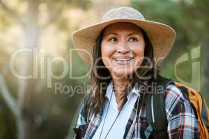 . Hiking, adventure and exploring with a mature female hiker enjoying a walk or hike in the forest or woods outside. Senior woman walking on a journey of discovery in nature in the great outdoors.