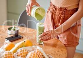 Closeup of a female pouring green healthy smoothie to detox, drinking vitamins and nutrients. Woman nutritionist having a fresh fruit juice to cleanse and provide energy for healthy lifestyle