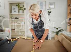 Fashion designer, tailor and seamstress measuring, preparing and making pattern for stylish, trendy and fashionable clothes. Mature woman in workshop, boutique or shop drawing design to make clothing