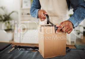 . Packing parcel, package or delivery order with black tape while packaging, boxing and wrapping product. Closeup of a small business owner or tailor wrapping a box for courier shipping or selling.