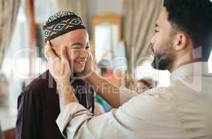 Affectionate, loving and caring Muslim father and son talking and bonding on Eid holiday. Cute, smiling and happy Islamic child listening to advice from dad while wearing a traditional outfit