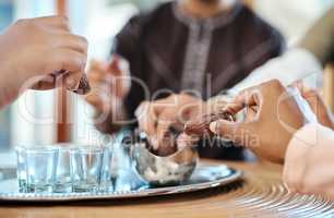 Muslim, islamic religion and spiritual arab family break their fast ready to eat dates together inside. Closeup of hands eating a date for eid before dinner celebrating the end of the ramadan holiday
