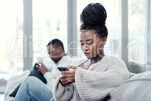 Angry, serious and annoyed woman giving her boyfriend the silent treatment or cold shoulder after a fight, argument or disagreement as a couple. Female reading a text and ignoring her husband at home