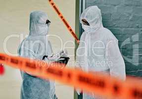 Forensic investigators collecting evidence at a murder scene in a building with barrier tape. Criminal researchers investigating a crime site and talking about the incident or case