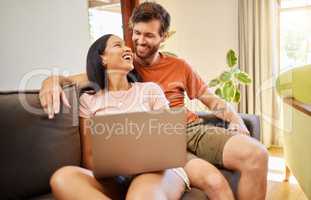 Couple talking and browsing on a laptop while relaxing on a sofa at home. Girlfriend and boyfriend scrolling on social media or the internet with technology while having conversation in living room.