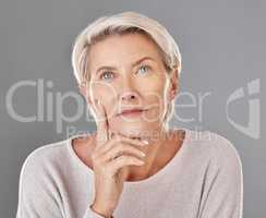 Mature, thinking and woman touching her face in isolated grey studio background. Copy space for anti ageing skincare or cosmetic products for senior feeling her skin and wrinkles headshot.