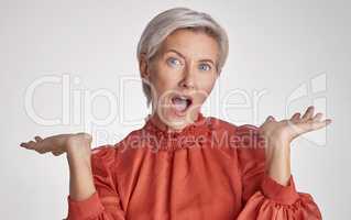 Mature surprised, wow and shocked woman face against a grey copy space grey studio background posing with her hands up and feeling unsure. Portrait of senior model making facial expression or emotion