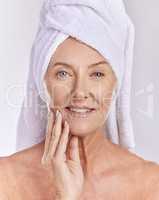 Skincare, health and beauty, a senior woman, towel on head, and smile on her face, taking care of her skin after a shower. Portrait of happy, mature, elderly female and healthy treatment for wrinkles