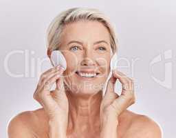 Grooming, skincare and hygiene by a mature woman apply cleanser or toner to her face with cotton pads. Senior female remove makeup and enjoying a routine pamper facial treatment against copy space