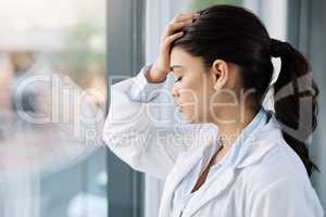 The reality is that not every life can be saved. a young female doctor looking stressed out while standing at a window in a hospital.