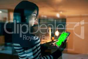 Maintaining her online presence as a business. a young businesswoman working late on a digital tablet with a chroma key screen in an office.