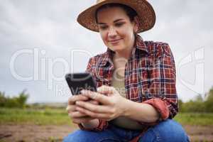 Farmer texting or scrolling on social media on a phone for online sustainability tips relaxing on an organic farm. Nature activist browsing and searching the internet for sustainable farming ideas