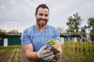 Happy farming worker with a plant on an agriculture farm with a smile. Farmer advertising sustainability, growth and ecology on a green field or land in a nature eco friendly environment countryside