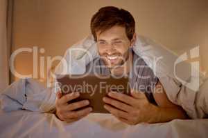 Happy man relaxing in bed with digital tablet watch, movie, series or online social media videos on an app. Browsing the internet news with 5g technology on wireless device in the bedroom at home