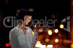 Dialing his number after dark. an attractive young woman using a mobile phone outside in the city at night.