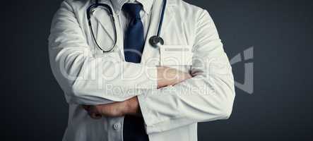 Confident in his medical ability. Studio shot of an unrecognizable male doctor standing with his arms folded against a dark background.