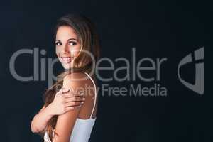 Theres a special charm to her beauty. Studio portrait of an attractive young woman posing against a dark background.