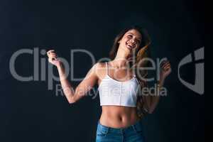 Just lose yourself in the beat. Studio shot of an attractive young woman dancing against a dark background.