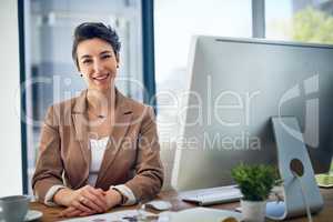 Hard work leaves so many rewards to reap. Portrait of a businesswoman working at her desk in an office.