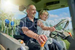 She wants to be just like dad. a male farmer and his daughter inside the cockpit of a modern tractor.