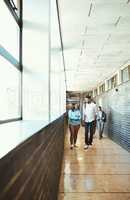 Arriving on campus for their first class. Full length shot of a group of university students walking through a campus corridor.