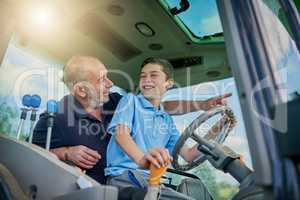 Eyes on the road. a male farmer and his son inside the cockpit of a modern tractor.