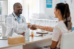 Healthcare, insurance and handshake between a doctor and patient consulting in an office, discussing a treatment plan. Happy woman smiling, satisfied with expert advice from health care professional