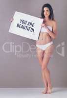 Always have been and always will be. Studio portrait of an attractive young woman holding a sign that reads you are beautiful against a pink background.