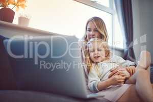 The internet is a great source for family friendly entertainment. an adorable little girl using a laptop with her mother on the sofa at home.